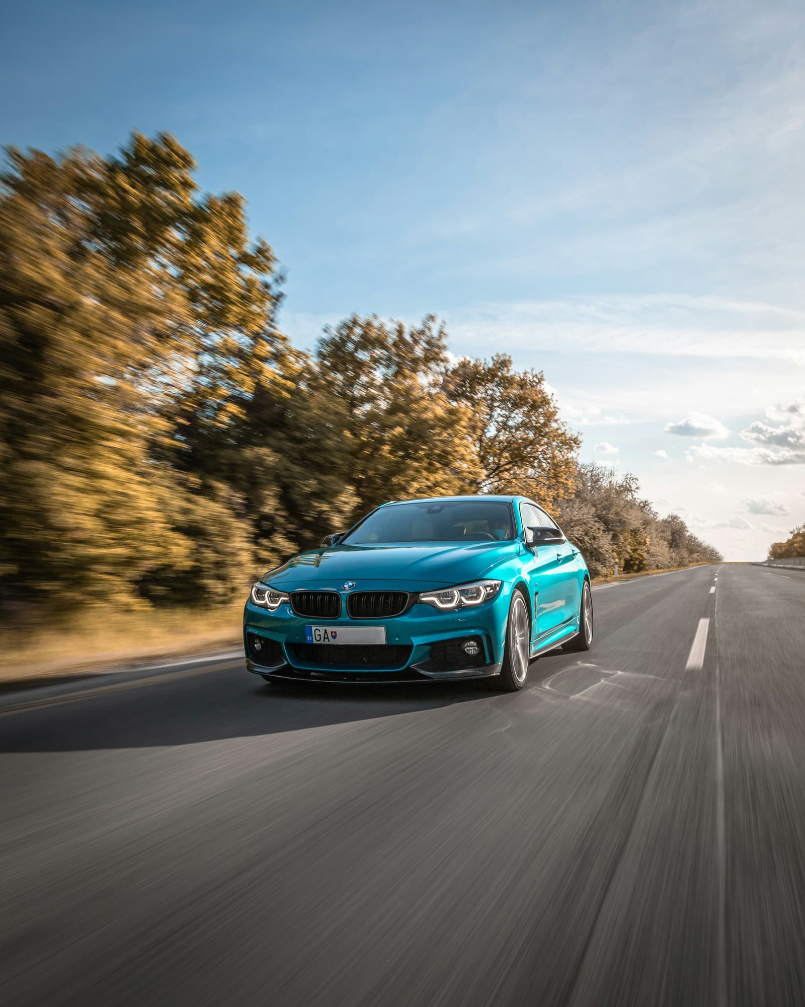 Teal BMW 4 Series coupe driving on a scenic highway