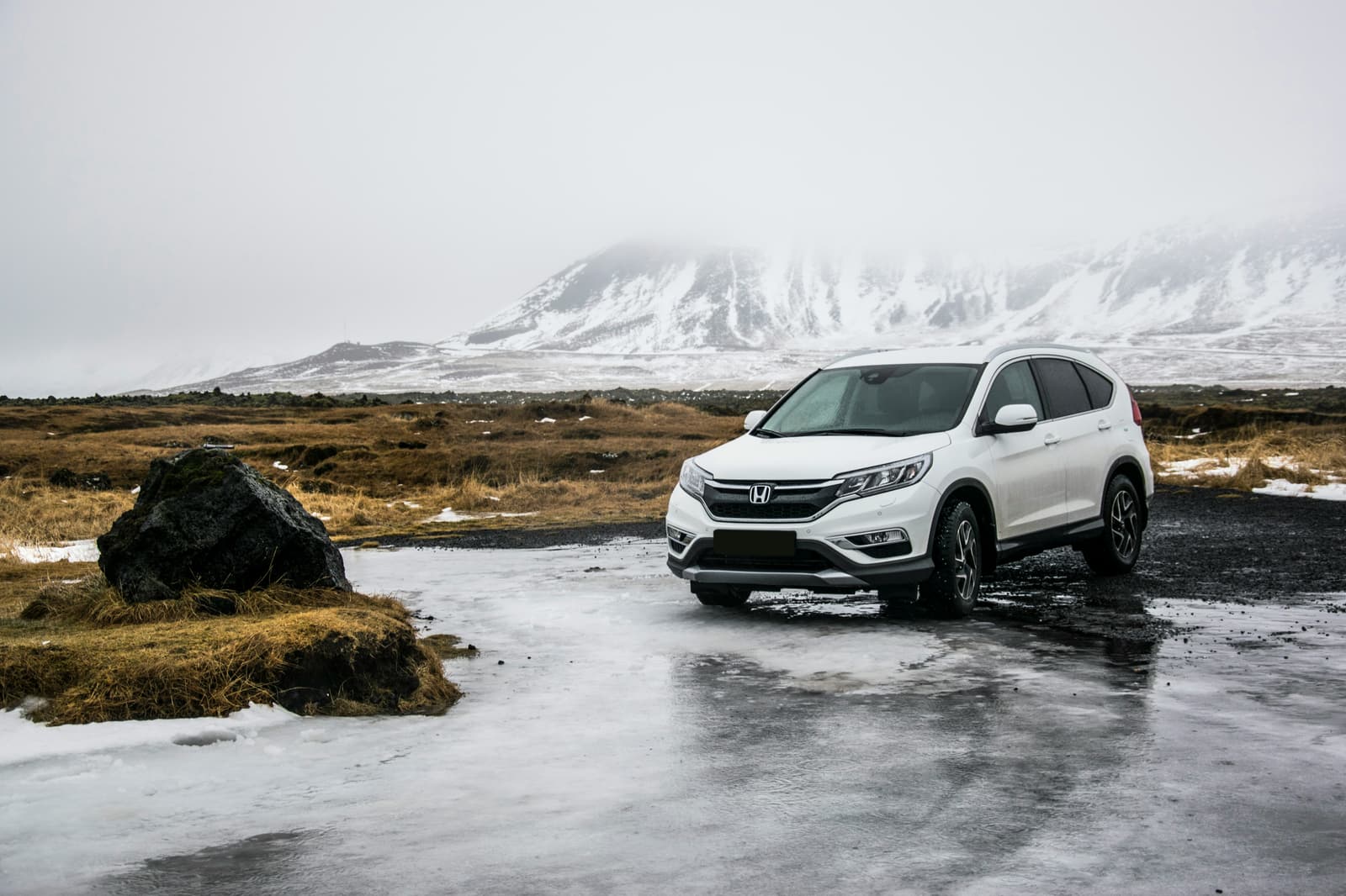 White Honda CR-V SUV parked in a snowy mountain landscape