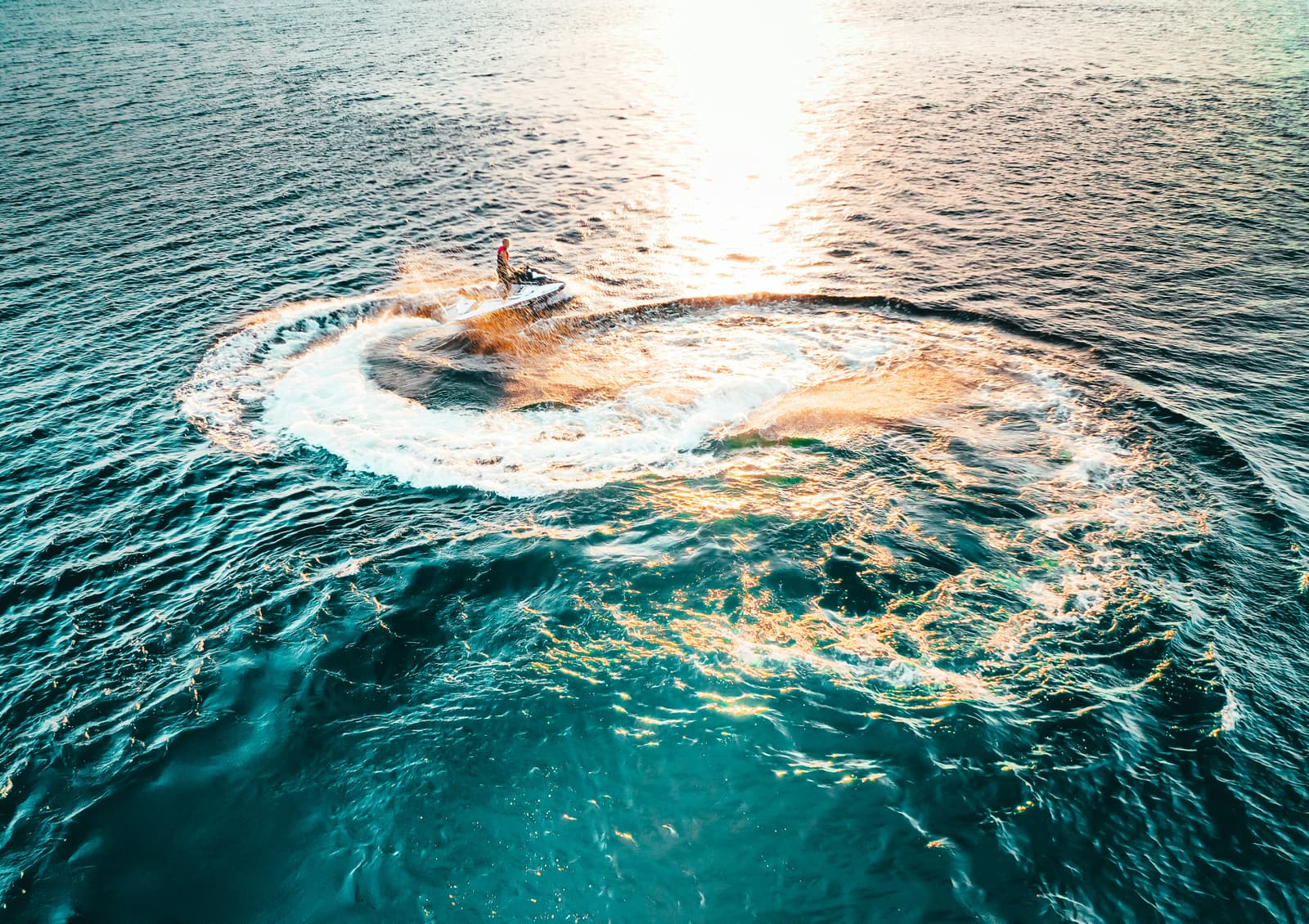 Aerial view of jet ski doing circles on turquoise ocean water