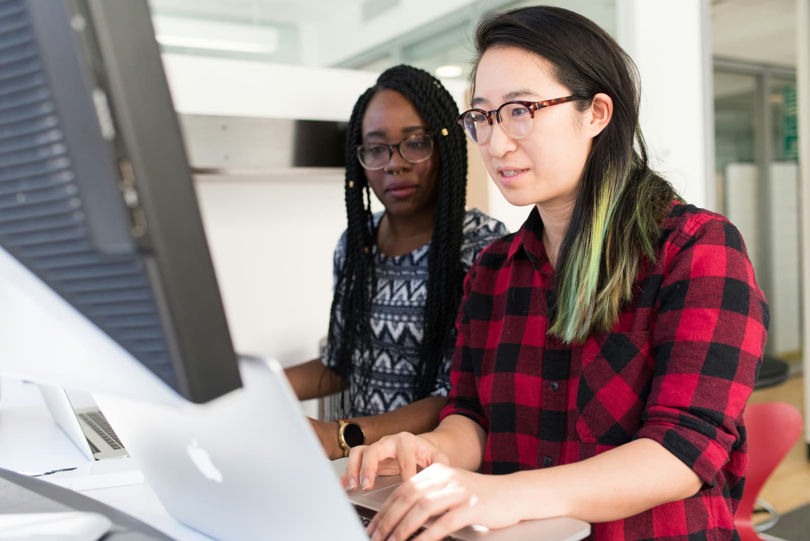Two women collaborating at computer workstations