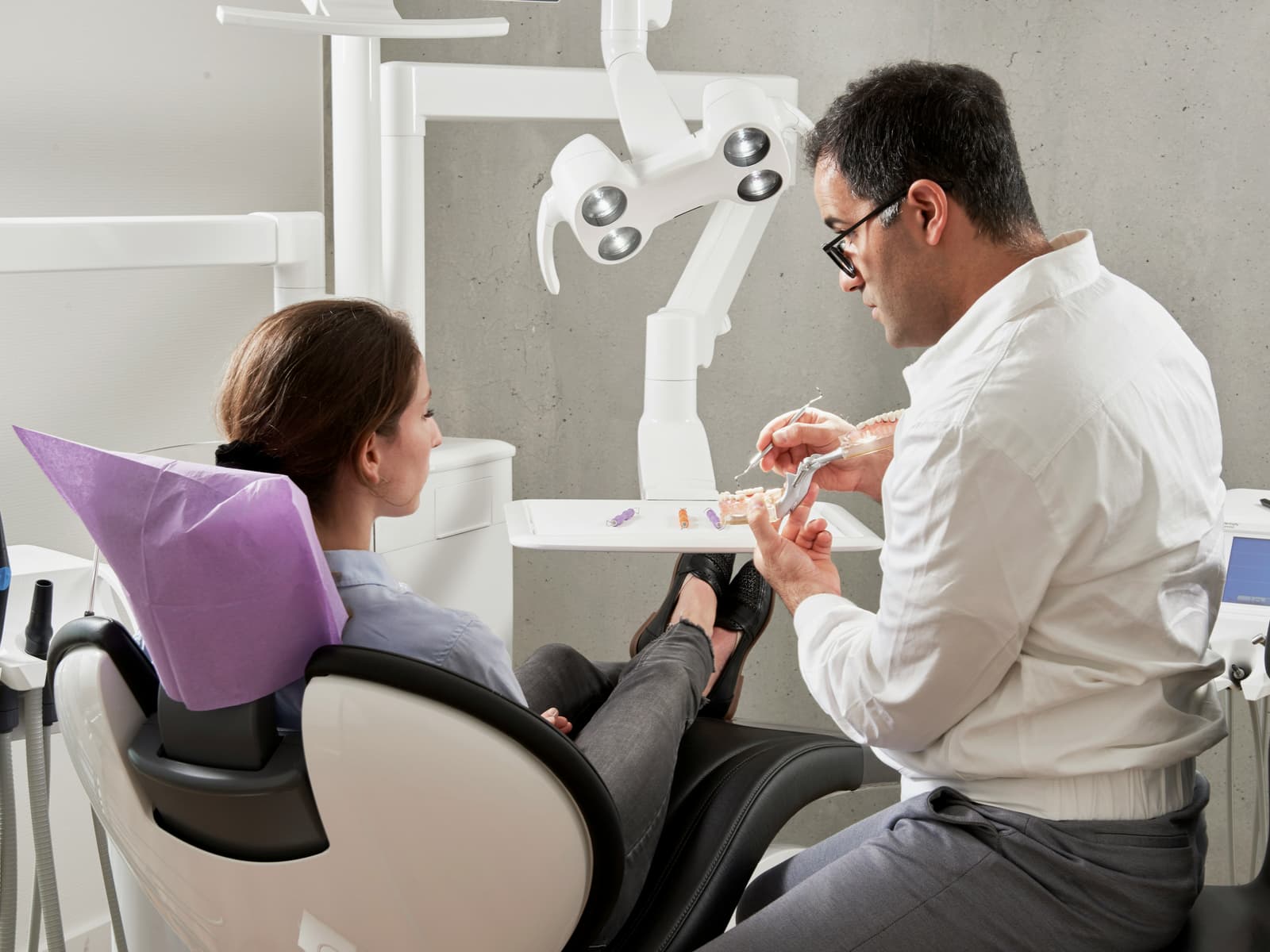 Dentist consulting with patient and explaining dental model