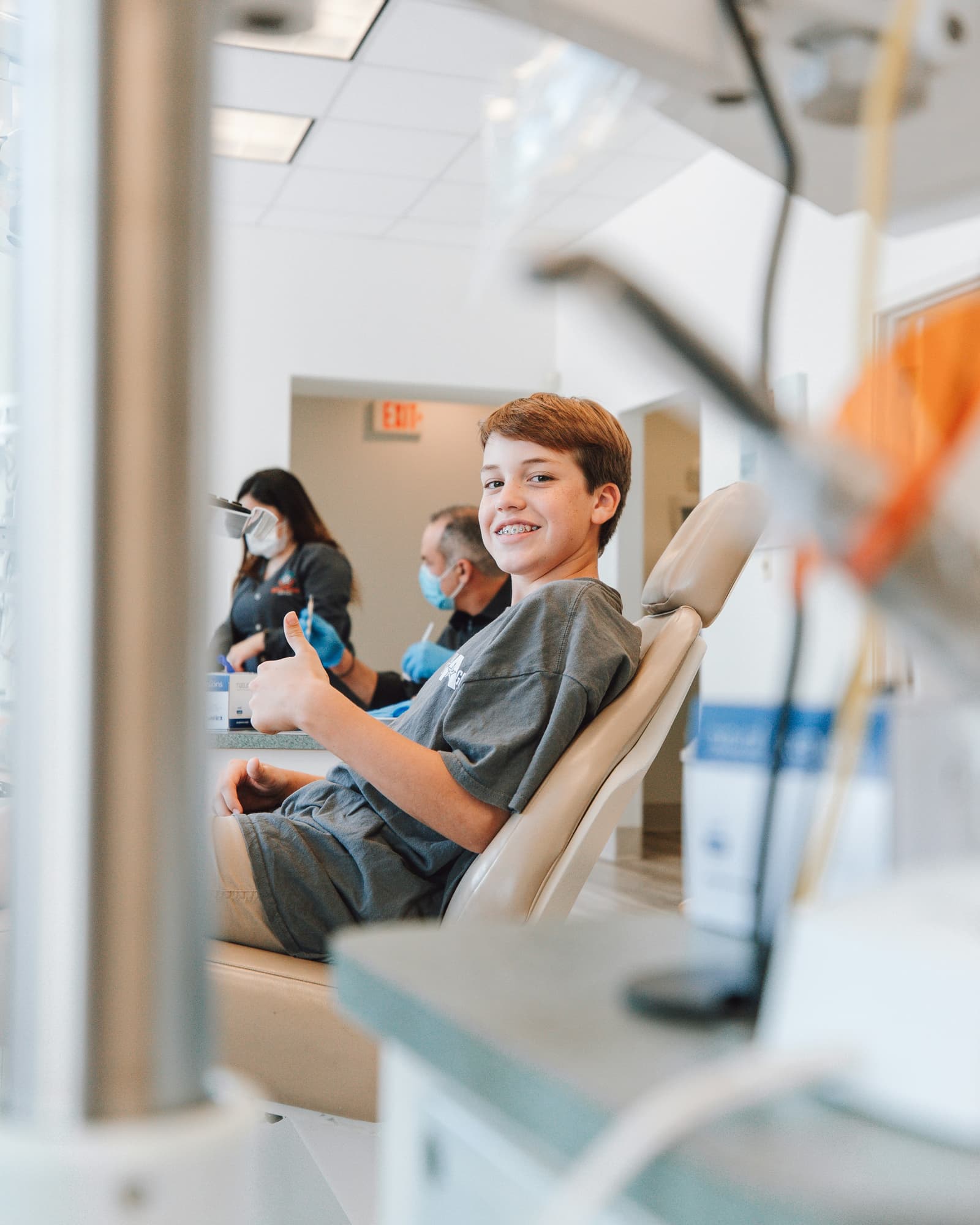 Young patient smiling and giving thumbs up in a dental chair