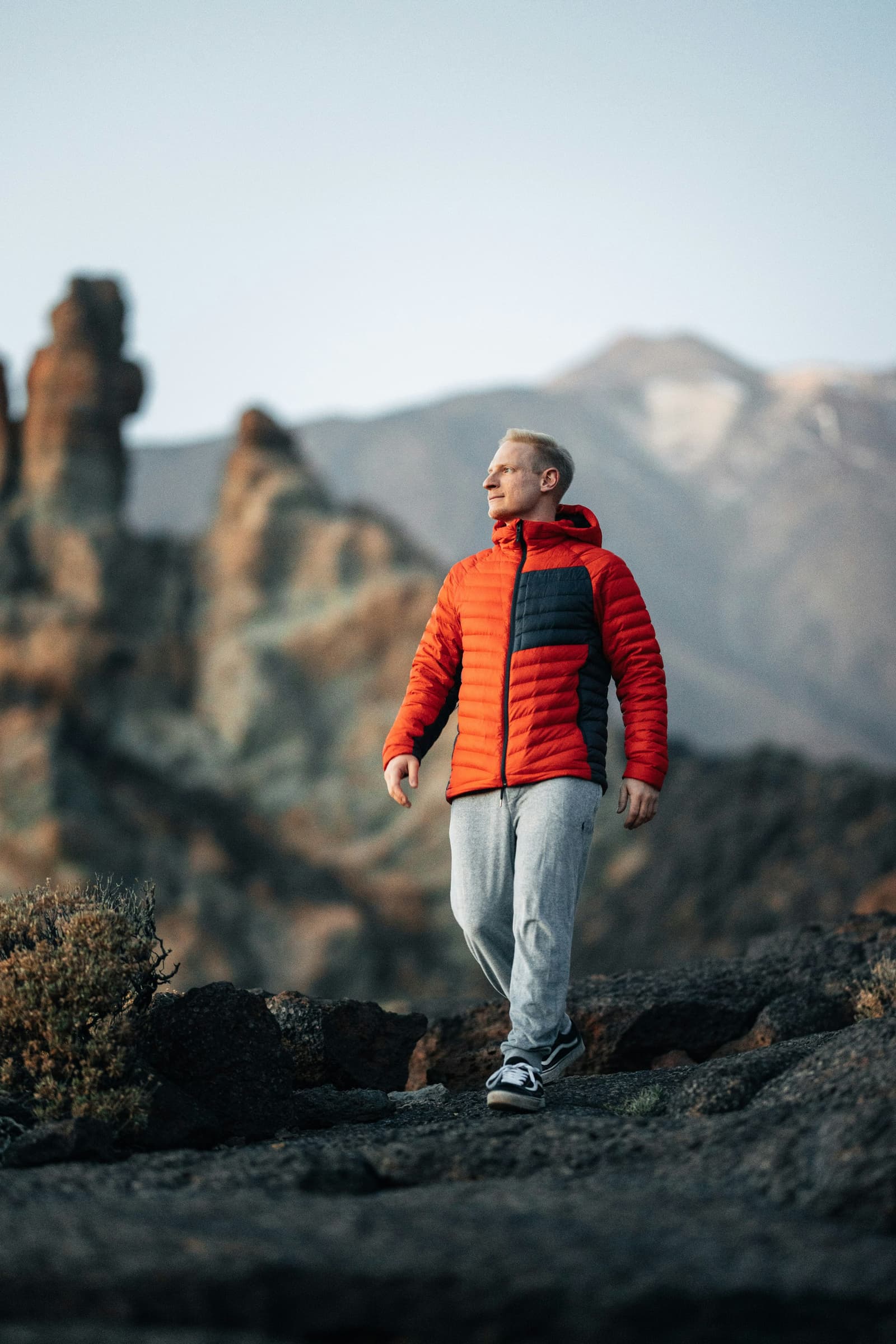 Man wearing orange puffer jacket in mountain landscape