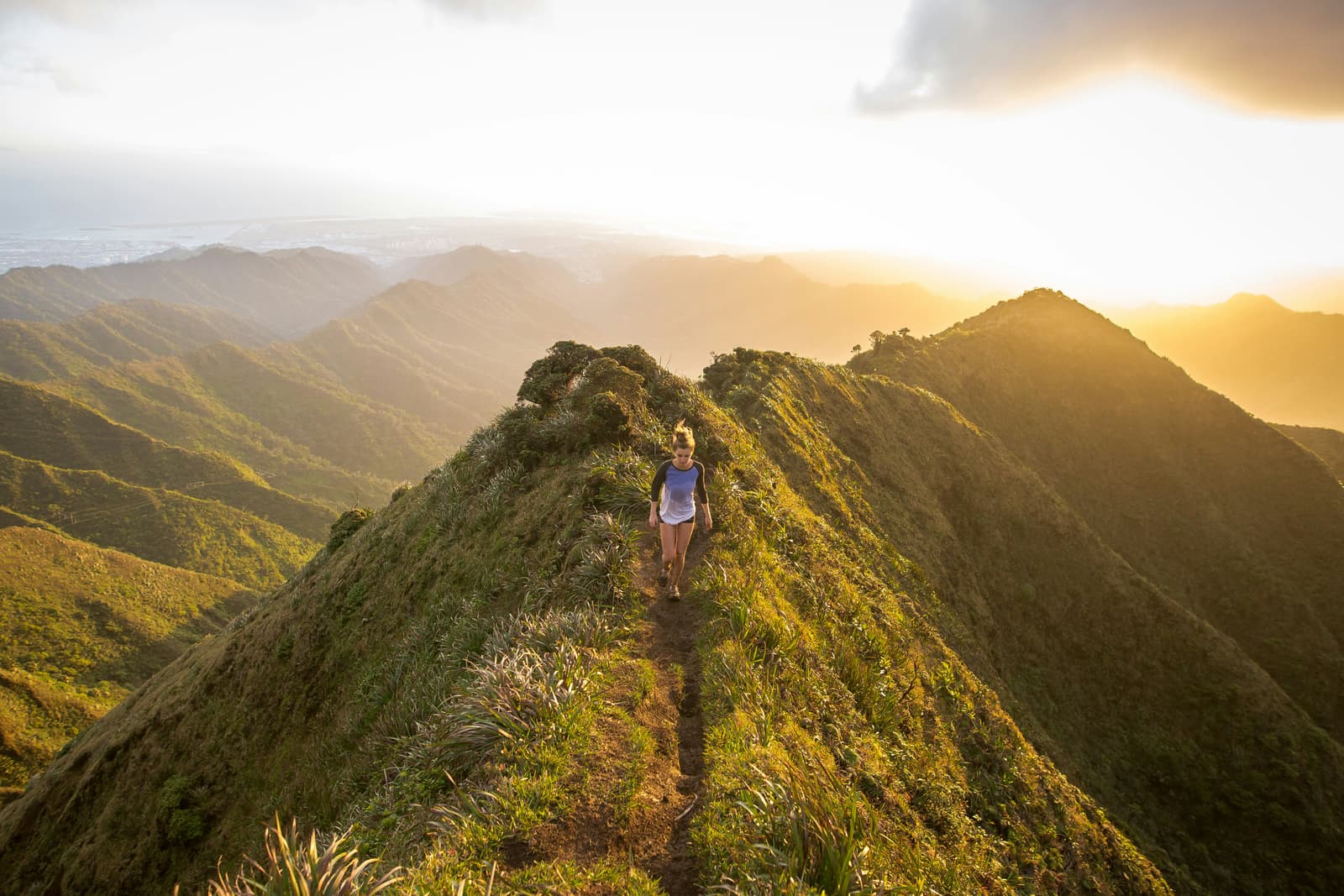 Hiker walking along a dramatic mountain ridge at golden sunset