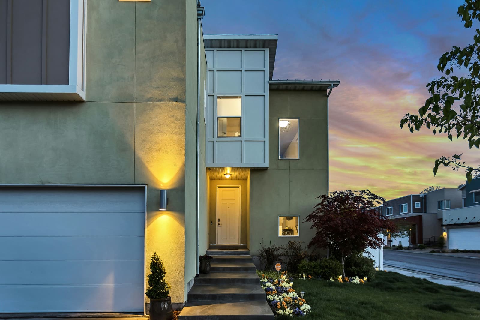 Modern townhome exterior at twilight with warm lighting