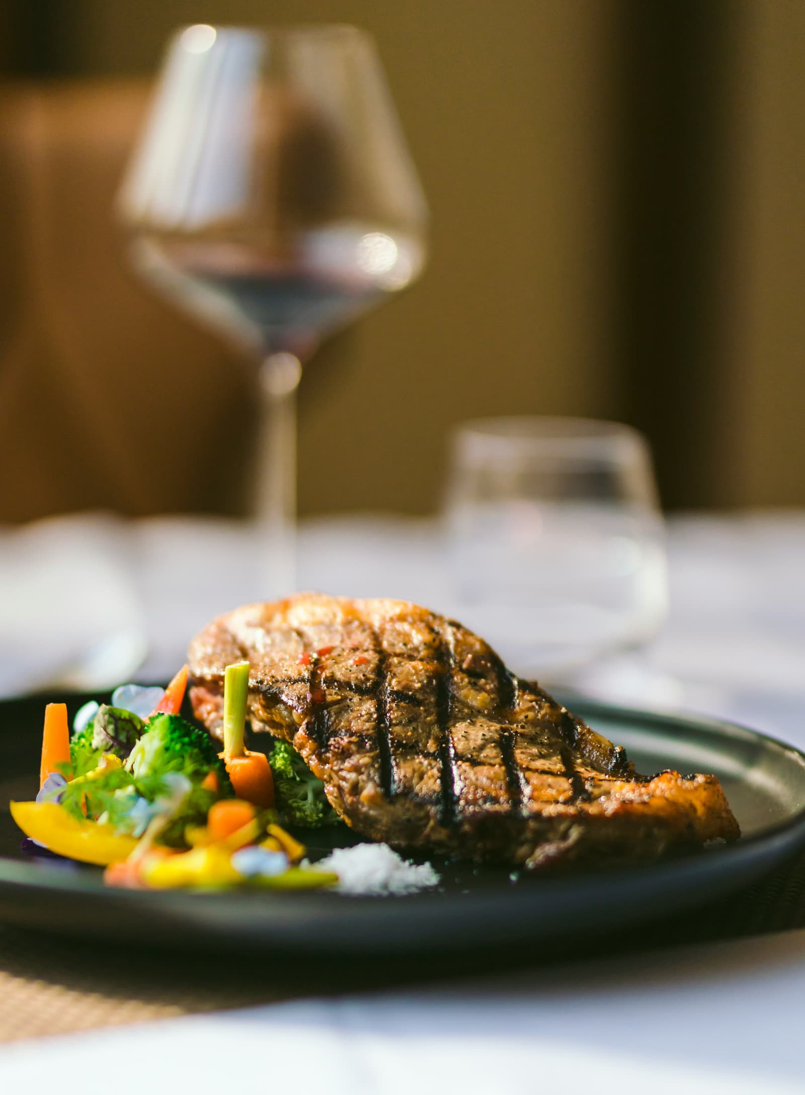 Grilled steak with colorful roasted vegetables and a glass of red wine